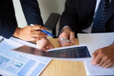 investor-broker-discussing-trading-strategy-holding-papers-with-financial-charts-pens-cropped-shot-broker-job-investment-concept